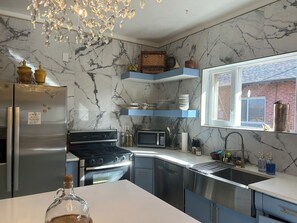 A modern kitchen with marble backsplash, stainless steel appliances, and blue cabinetry. - Where Design Meets Comfort - Modern 3BR at Sloan’s Lake (Denver)