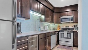 A modern kitchen with dark wooden cabinets, stainless steel appliances, and a tiled backsplash. - Updated 2 Bed 2 Bath Condo on beautiful Lake Hamilton 7 minutes from Oaklawn!! (Lake Hamilton)