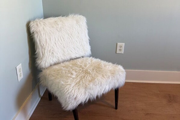 Una silla con un asiento y respaldo blancos y mullidos, frente a una pared azul claro.