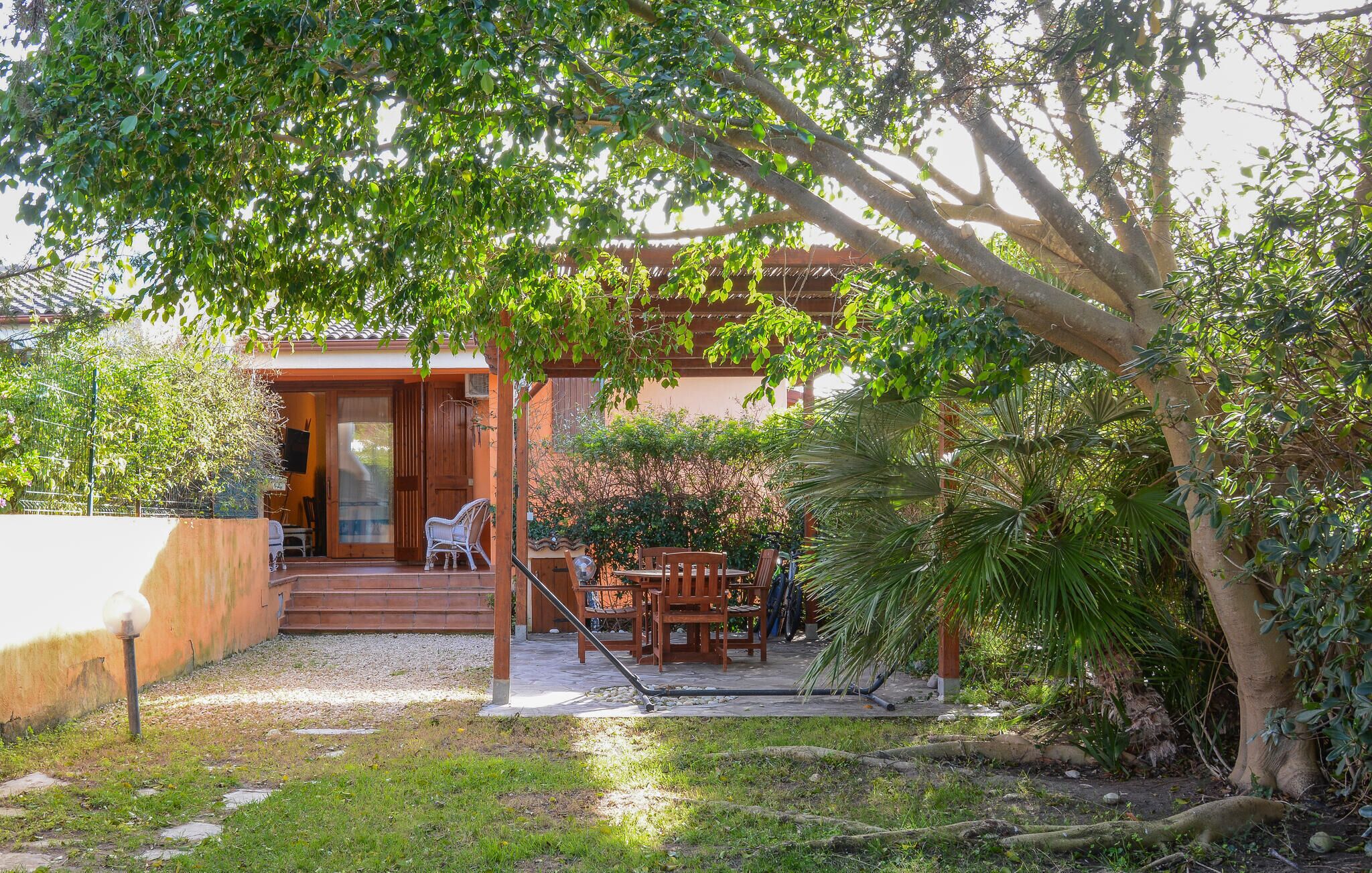 A house with a covered patio, outdoor seating, and a garden.