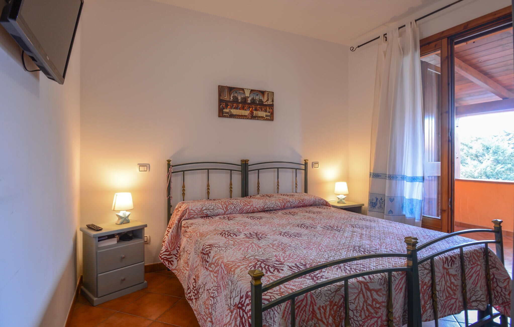 Een slaapkamer met een bed, twee nachtkastjes met lampen, een schilderij aan de muur en een raam met gordijnen.