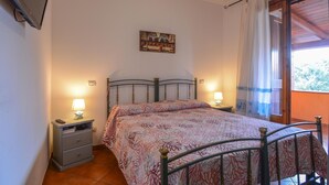 Une chambre à coucher avec un lit, deux tables de chevet avec des lampes, un tableau au mur et une fenêtre avec des rideaux.
