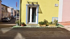 Um edifício amarelo com uma porta, plantas em vasos e uma placa de proibido estacionar.