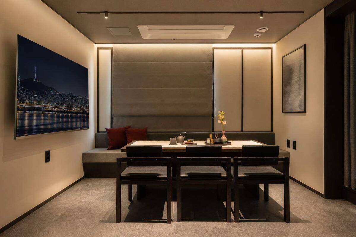A modern dining area with a table set for four, a large window with a cityscape view, and a seating bench with cushions.