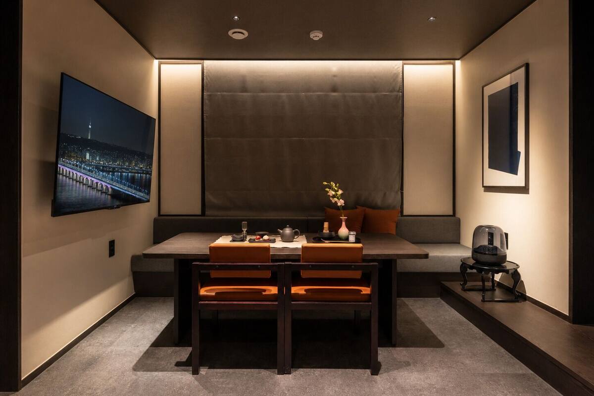 A modern room with a dining table, chairs, a sofa, a TV, and a coffee machine.