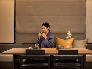 A person seated at a table with a laptop, a cup, and a vase with flowers. - Loop Seoul Hotel by Anook Seoul Gangnam 1 (Seoul)