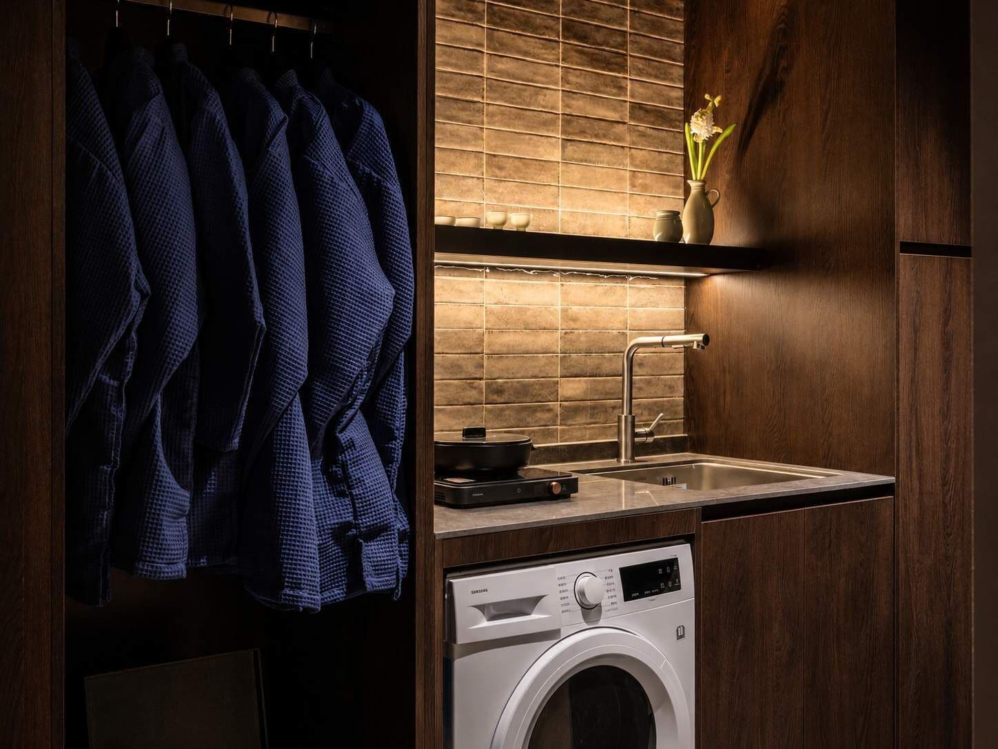 A modern kitchen with a built-in washing machine, a sink, and a hanging rack for clothes.