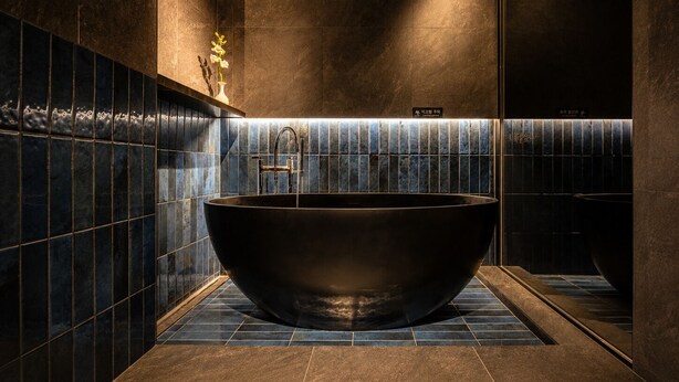 A modern bathroom with a large freestanding bathtub, dark tiled walls, and a small vase with flowers. - Loop Seoul Hotel by Anook Seoul Gangnam 1 (Seoul)
