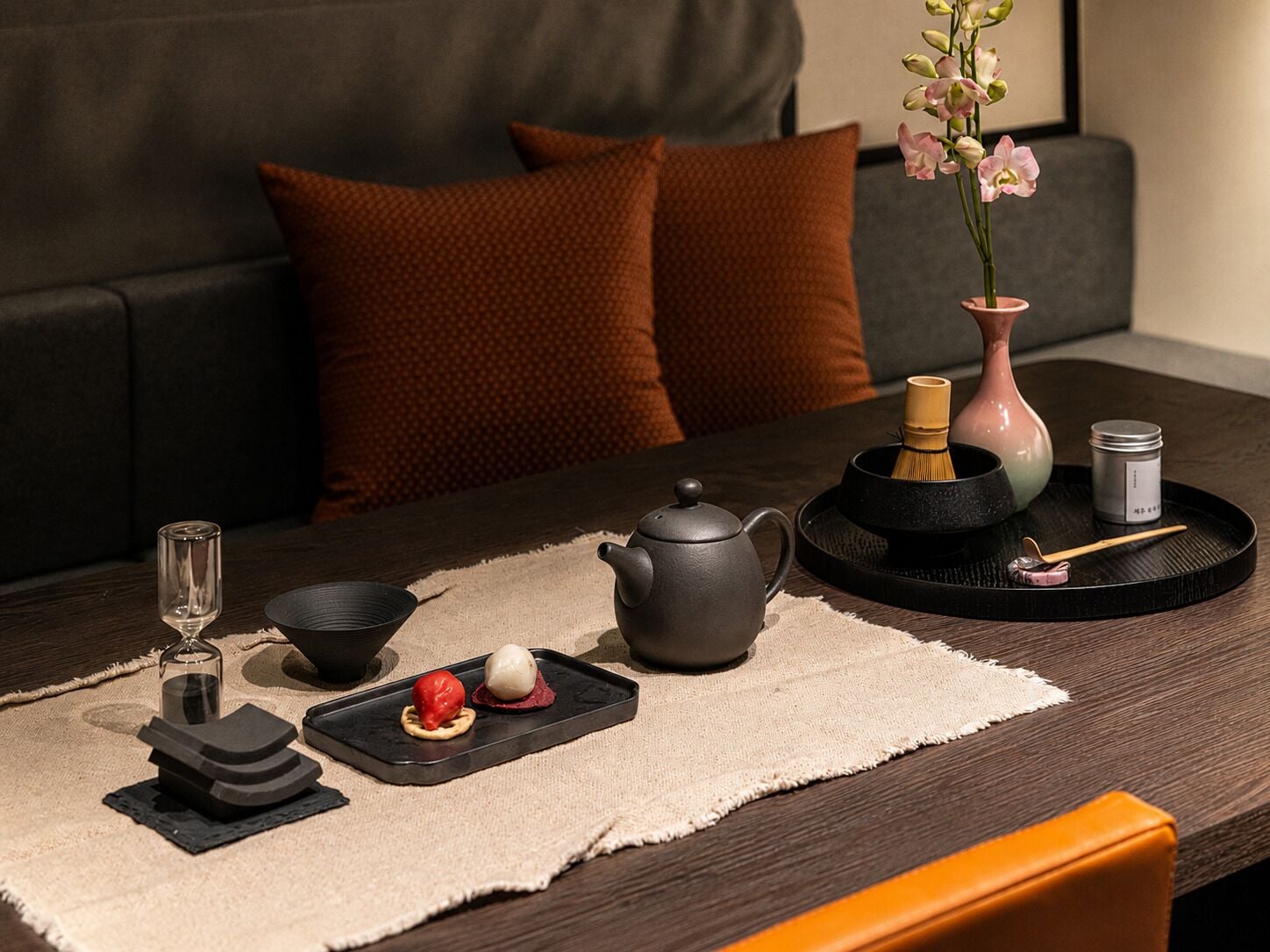 A dining setup with a teapot, cups, a tray, and a vase with flowers.