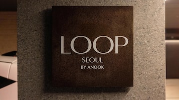 A sign with the text 'LOOP SEOUL BY ANOOK' on a textured wall.