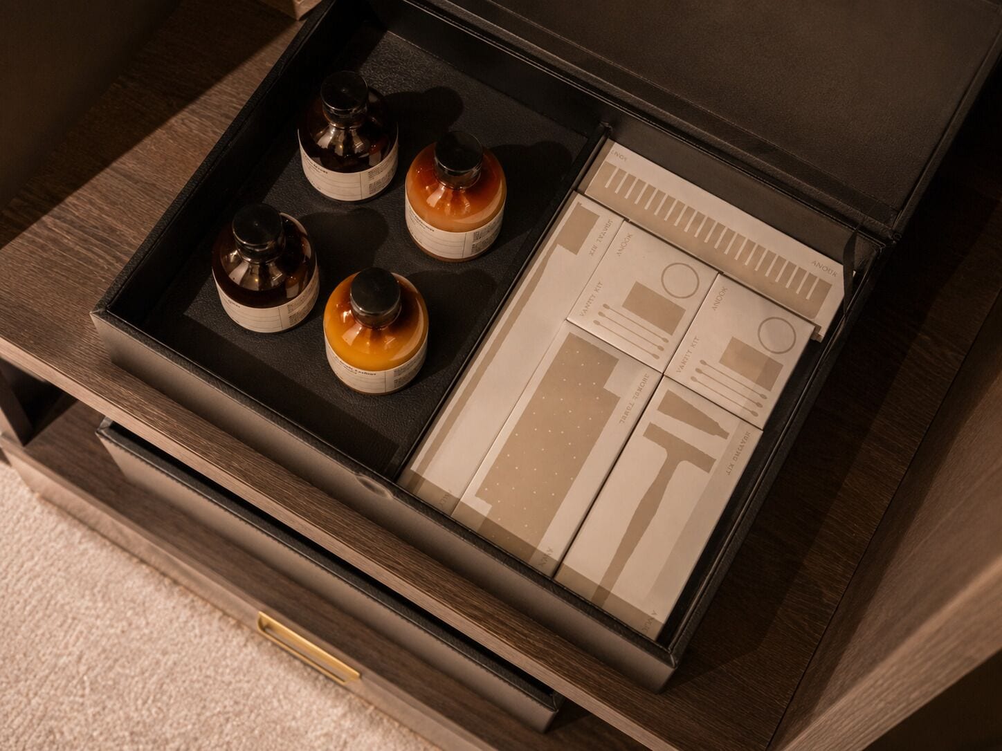 A wooden drawer with a black interior, containing four small containers and a set of cards.