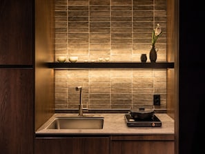 A modern kitchen with a built-in sink, a black induction cooktop, and a shelf with decorative items. - Loop Seoul Hotel by Anook Seoul Gangnam 1 (Seoul)