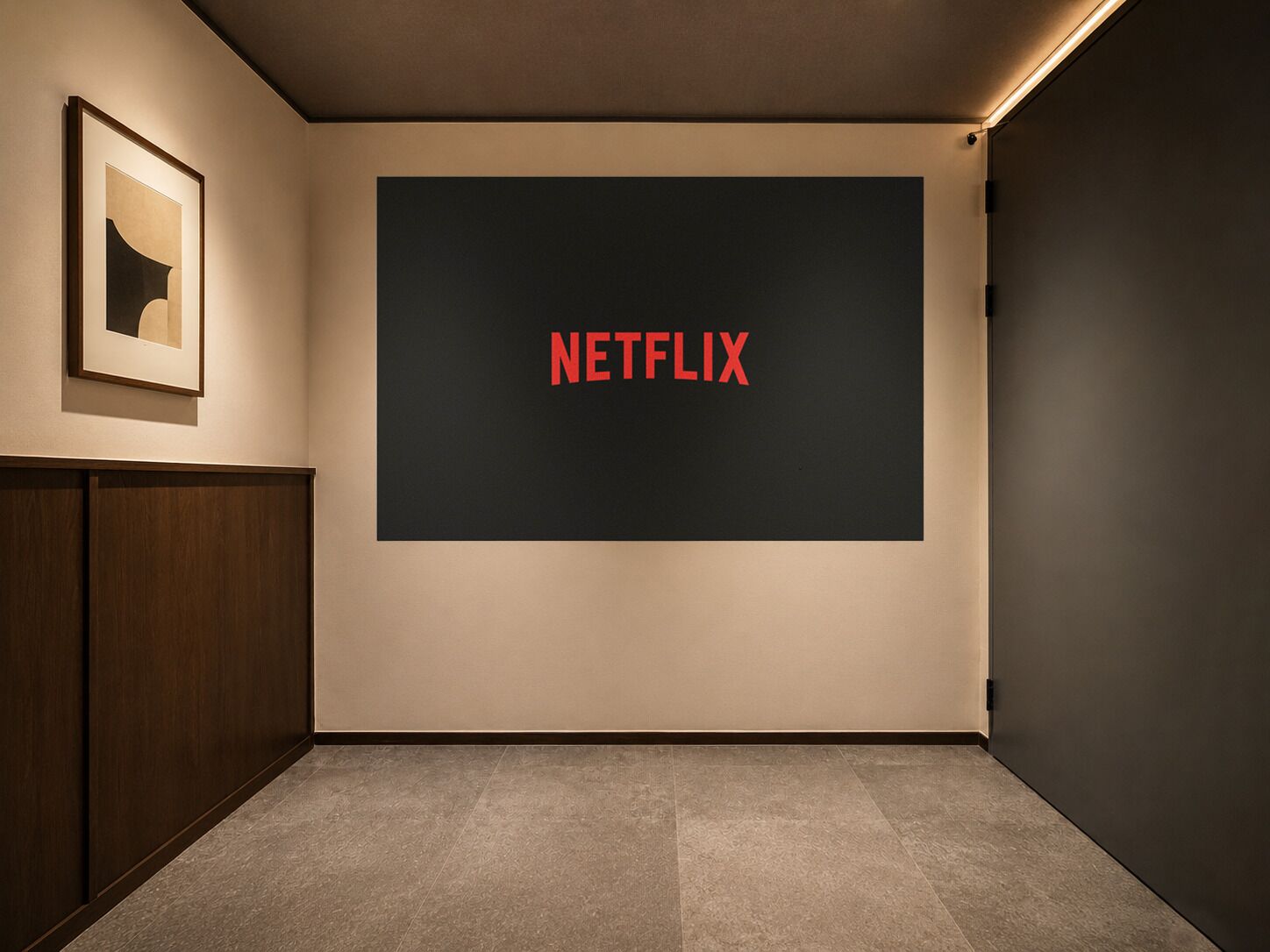 A room with a large screen displaying 'NETFLIX,' a framed picture on the wall, and a wooden cabinet.