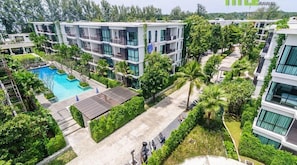 A modern multi-story residential building with balconies, a swimming pool, and lush greenery. - B108 Title Rawai Beach Front 1 Bed Apartment (Rawai)
