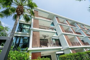 A multi-story hotel with balconies, large windows, and a palm tree in the foreground. - B108 Title Rawai Beach Front 1 Bed Apartment (Rawai)