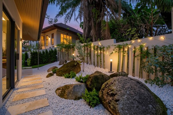 A modern house with a stone pathway leading to the entrance, surrounded by large rocks and greenery. - Tiwa Pool Villa Baan Bua 3 mins to Nai Harn Beach (Rawai)