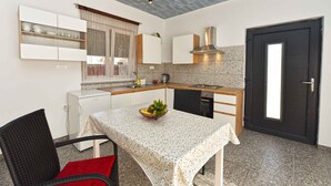 A compact kitchen with a dining table, a refrigerator, and a black door. - Studio mit Klimaanlage und Pool (Valbandon)