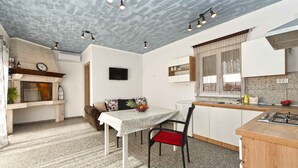 A compact kitchen with a dining area, a built-in oven, and a TV mounted on the wall. - Studio mit Klimaanlage und Pool (Valbandon)