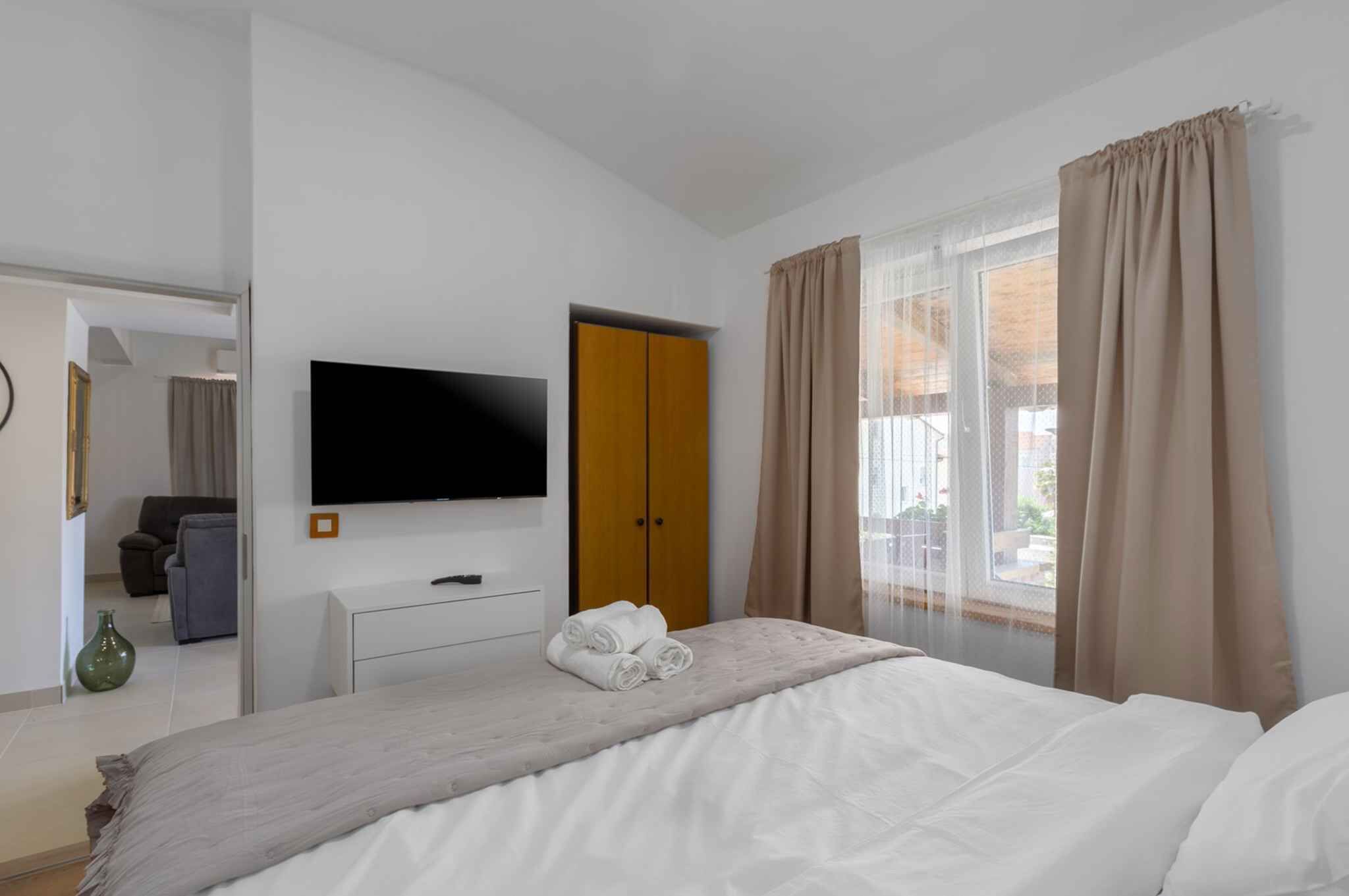 A hotel room with a bed, a TV, a wardrobe, and a window with curtains.