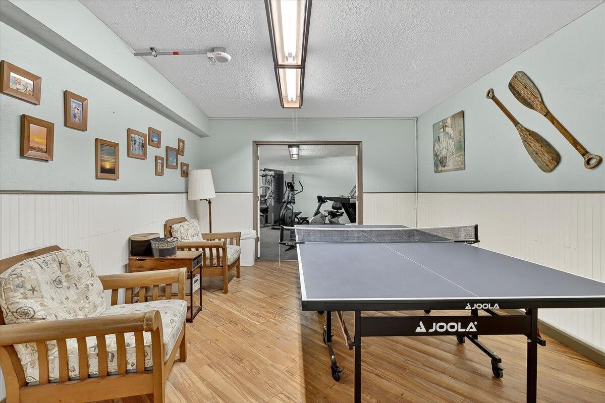 Ein Zimmer mit Tischtennisplatte, Holzmöbeln und an der Wand befestigter Trainingsausstattung.