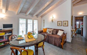 A cozy living room with a sofa, a dining table with chairs, and a television. - Beautiful apartment in Casarza Ligure with WiFi (Casarza Ligure)