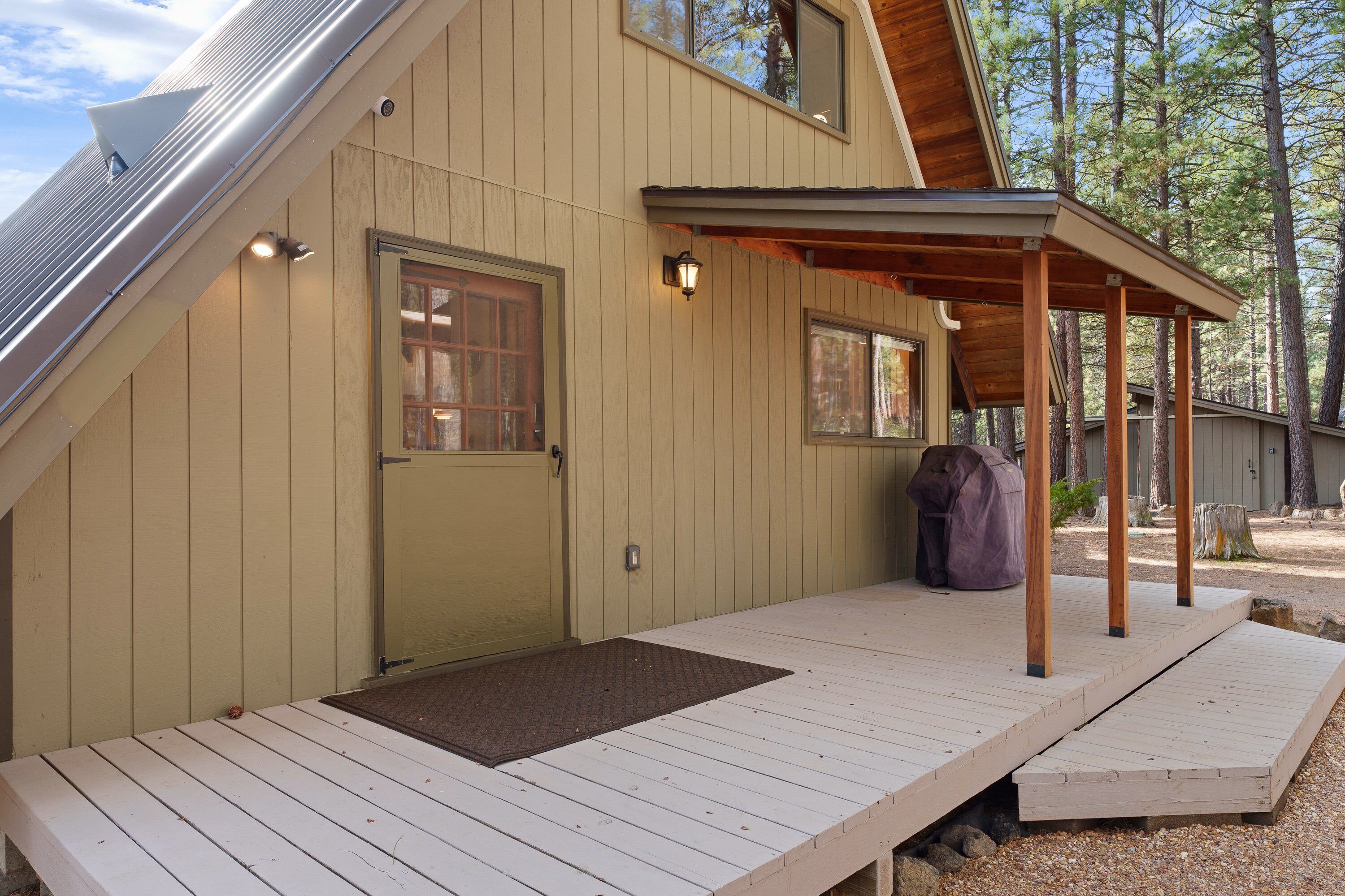 A wooden deck with a covered area, a door, and a window.