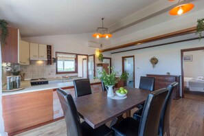 A modern kitchen with a central island, wooden cabinets, and a dining area with a table and chairs. - Villa mit Klimaanlage und Pool (Vižinada)