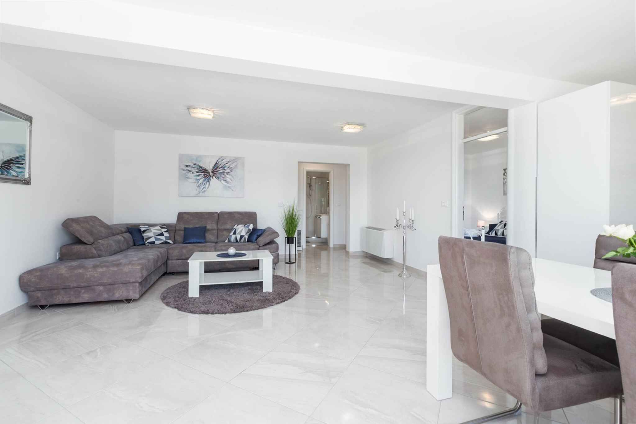 A modern living room with a sectional sofa, a coffee table, and a dining area with a white table and chairs.