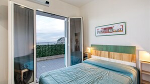 Une chambre d’hôtel avec un lit, un tableau au mur et une vue sur un paysage verdoyant par la fenêtre.