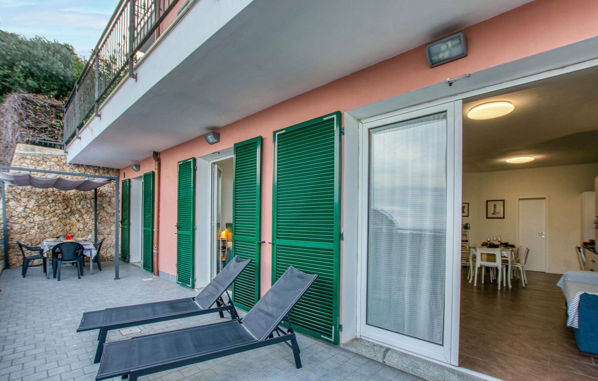 Un balcon avec deux fauteuils, une table avec des chaises et un mur en pierre.