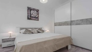 Ein modernes Schlafzimmer mit einem Bett, Nachttischen, einem Wandbild und einem Kleiderschrank.