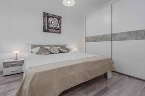 Ein modernes Schlafzimmer mit einem Bett, Nachttischen, einem Wandbild und einem Kleiderschrank.