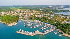 Eine Luftaufnahme einer Küstenstadt mit einem Yachthafen, Wohngebieten und einer großen Wasserfläche.