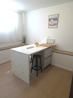 A compact kitchen with a marble countertop, a single stool, and a small island. - Holiday apartment near the beach (Tkon)