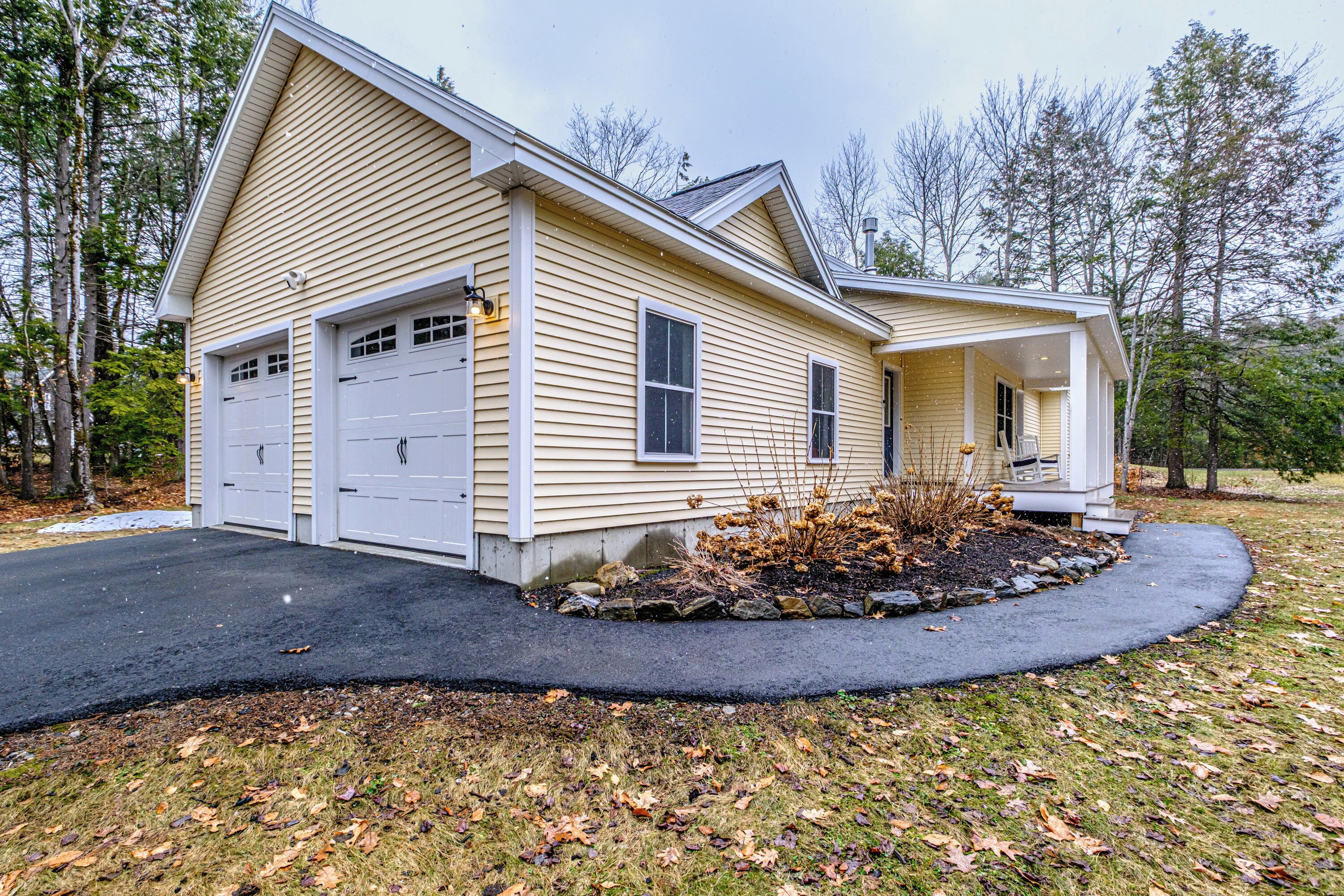 A two-story house with a garage, a covered porch, and a landscaped front yard.