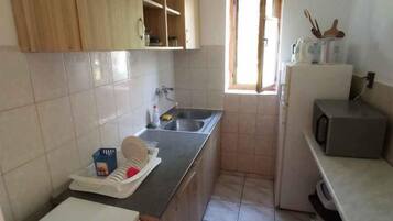 A compact kitchen with wooden cabinets, a sink, and a window.