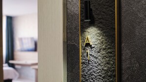 Tekstuuripintainen seinä, jossa on kultainen numero ’1’ ja musta valaisin.
