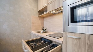 Moderni keittiö, jossa on puiset kaapit, ruostumattomasta teräksestä valmistettu allas ja sisäänrakennettu uuni.