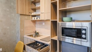 A compact kitchen with a built-in microwave, a sink, and wooden cabinets. - А17 Plovdiv Apartments Next to Rowing Channel app3 (Plovdiv)
