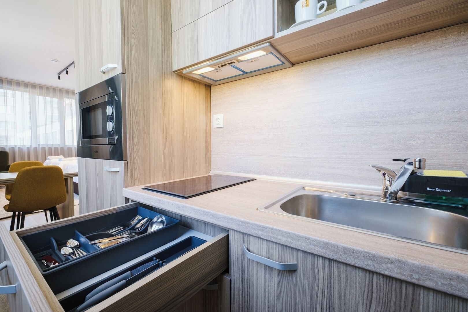 A modern kitchen with a built-in microwave, a stainless steel sink, and a compact dishwasher.