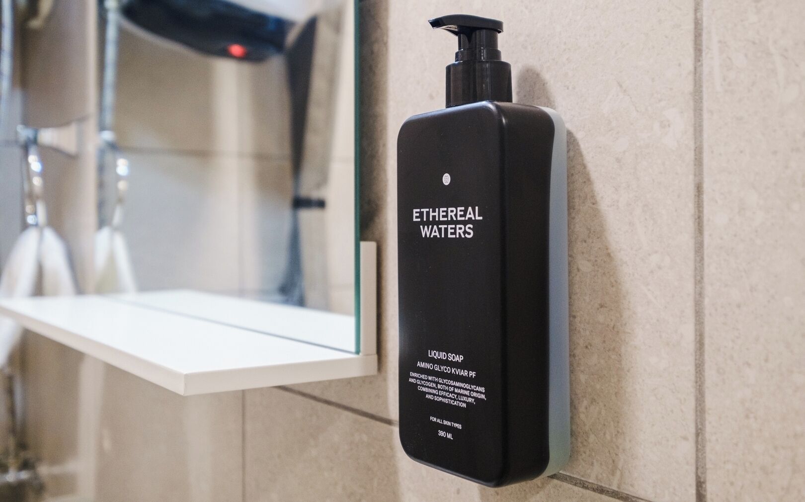 Un distributeur de savon noir portant l’inscription « EAU ÉTHÉRÉE » est fixé au mur d’une salle de bain.