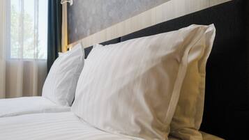 A neatly made bed with white linens and a dark headboard.