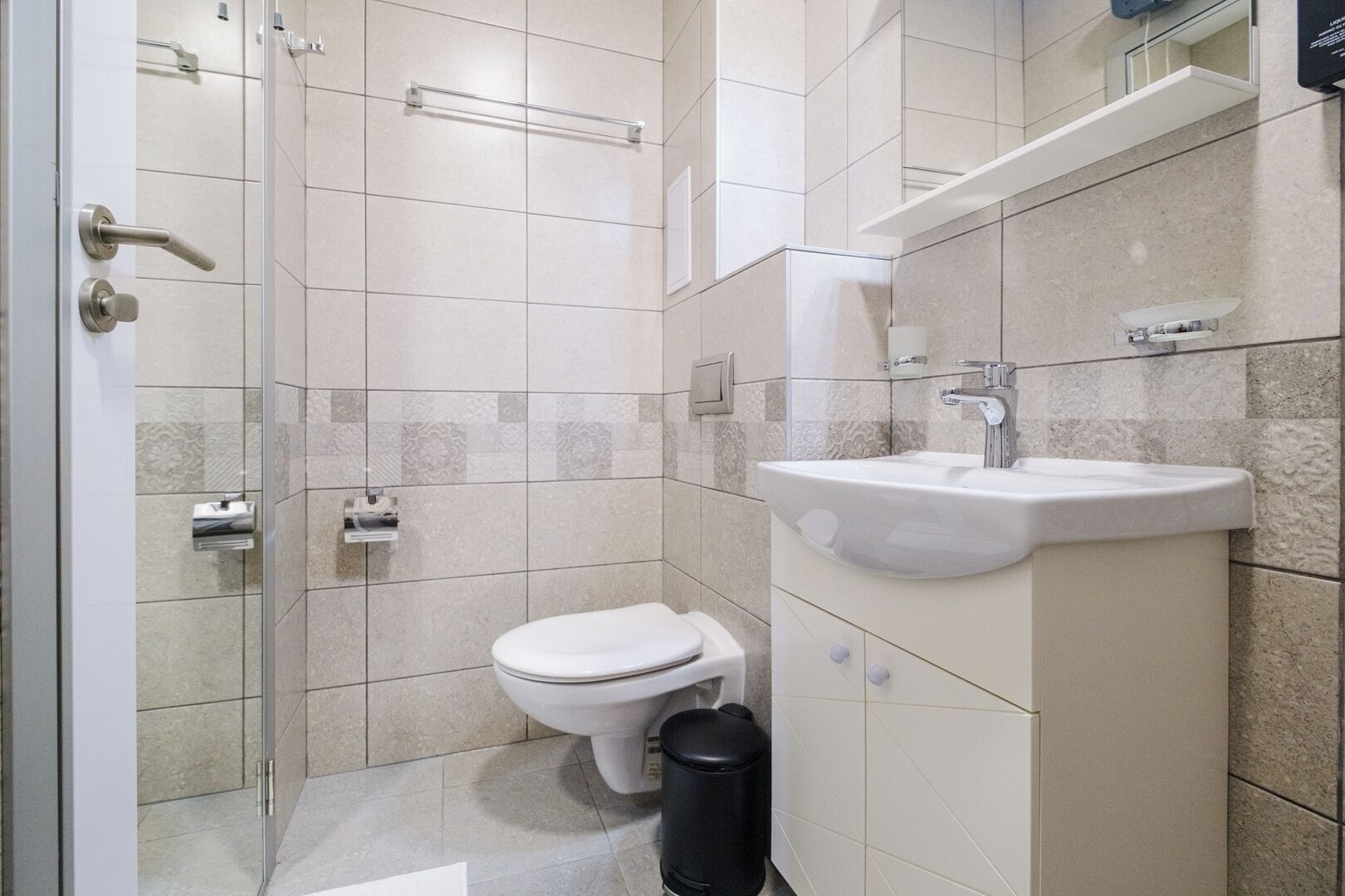 A modern bathroom with a toilet, sink, and glass shower enclosure.