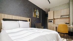 Una habitación de hotel moderna con una cama grande, un escritorio y un microondas.