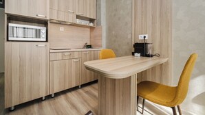 Una cocina moderna con armarios de madera, microondas, cafetera y una silla amarilla.