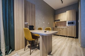 A modern kitchen with wooden cabinets, a microwave, and a dining area with a table and chairs.
