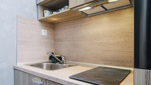 Une cuisine compacte dotée de deux éviers en acier inoxydable, d’un four encastré et d’un pare-feu en bois.
