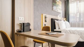 Une chambre d’hôtel avec un bureau en bois, une chaise, un lit avec une literie blanche et un tableau au mur.