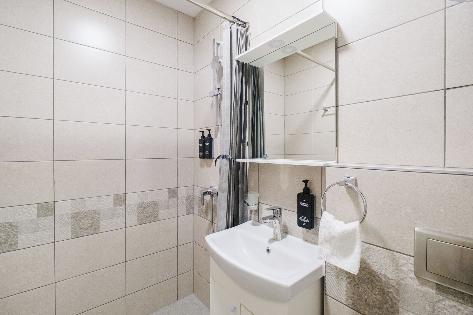 Une salle de bain moderne avec une douche, un lavabo et un miroir.