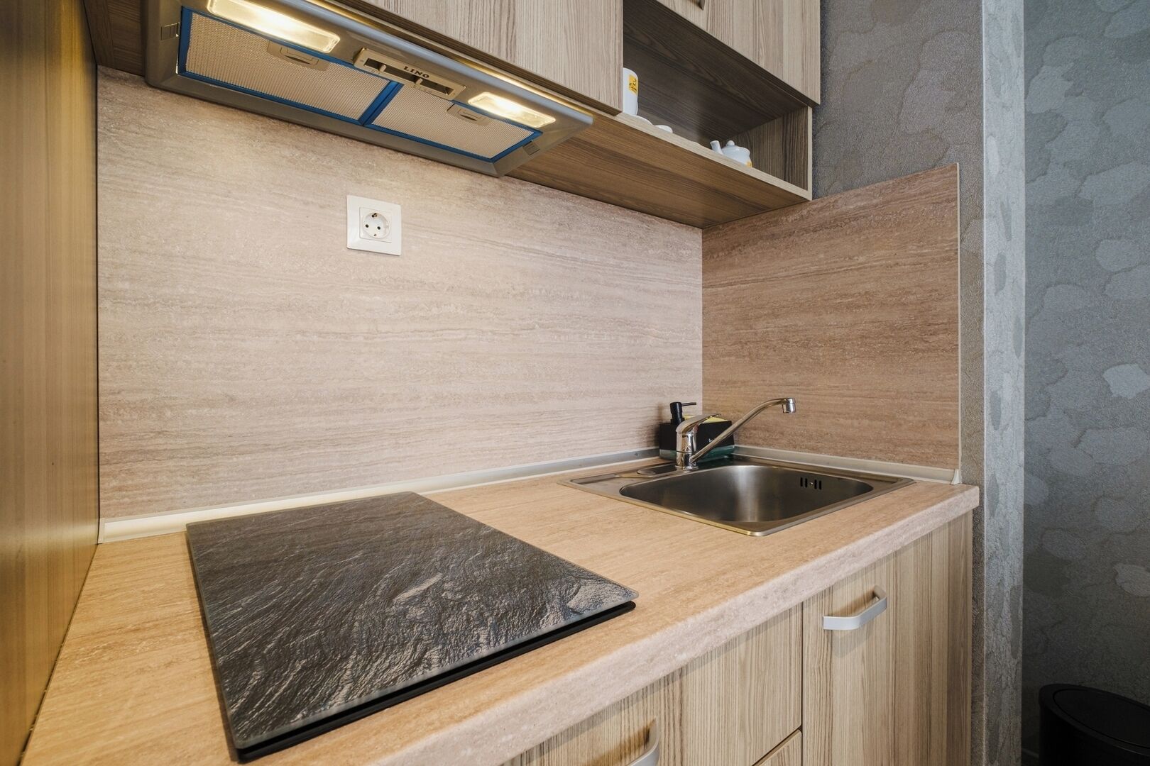 A modern kitchen with a stainless steel sink, wooden cabinets, and a built-in shelf above the countertop.